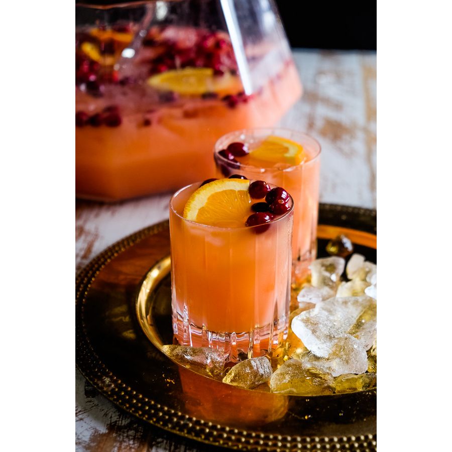 Two glasses of orange cocktail with garnishes on a gold tray.